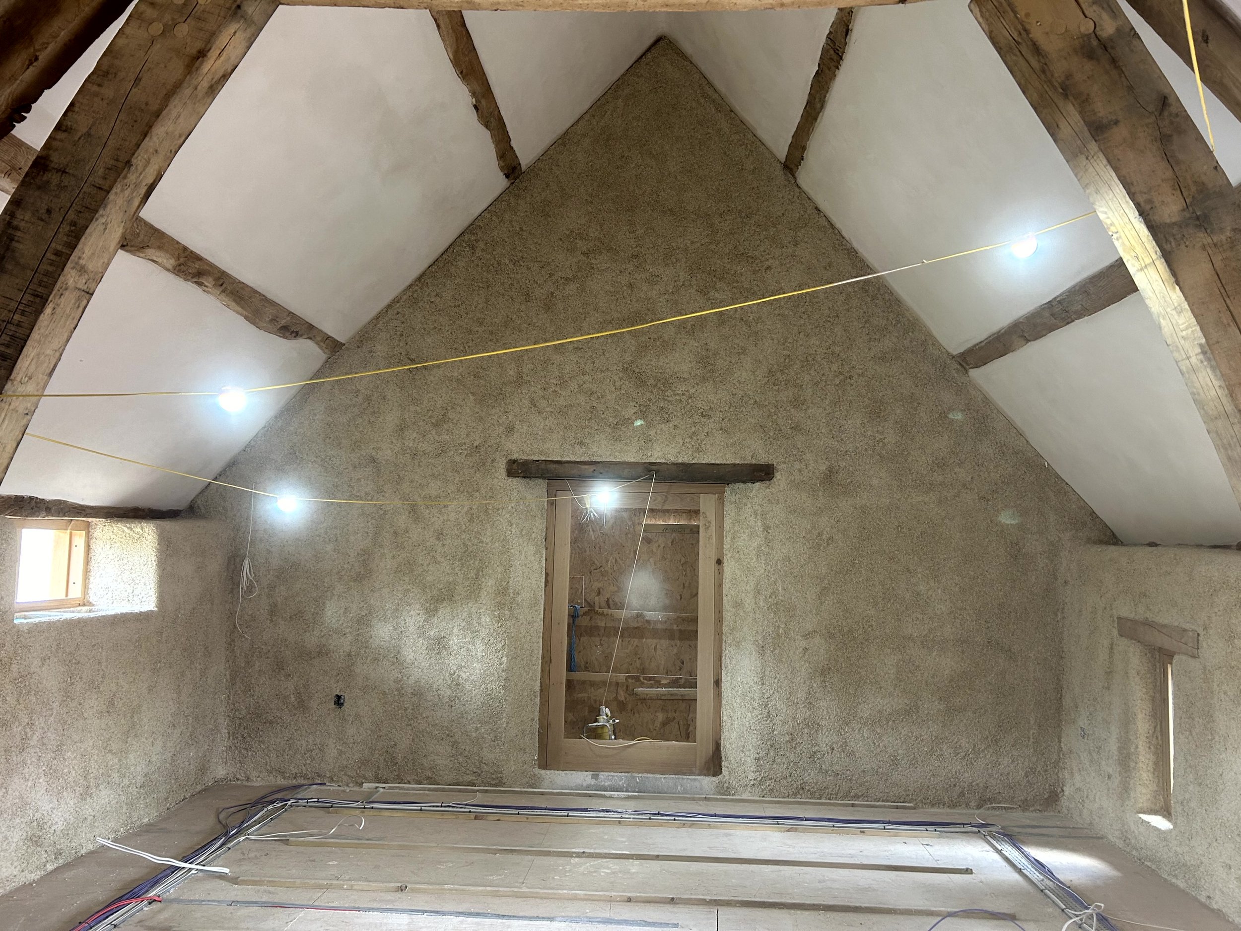 Another angle of the sprayed gable wall and oak A-frame, with small windows either side of the central door