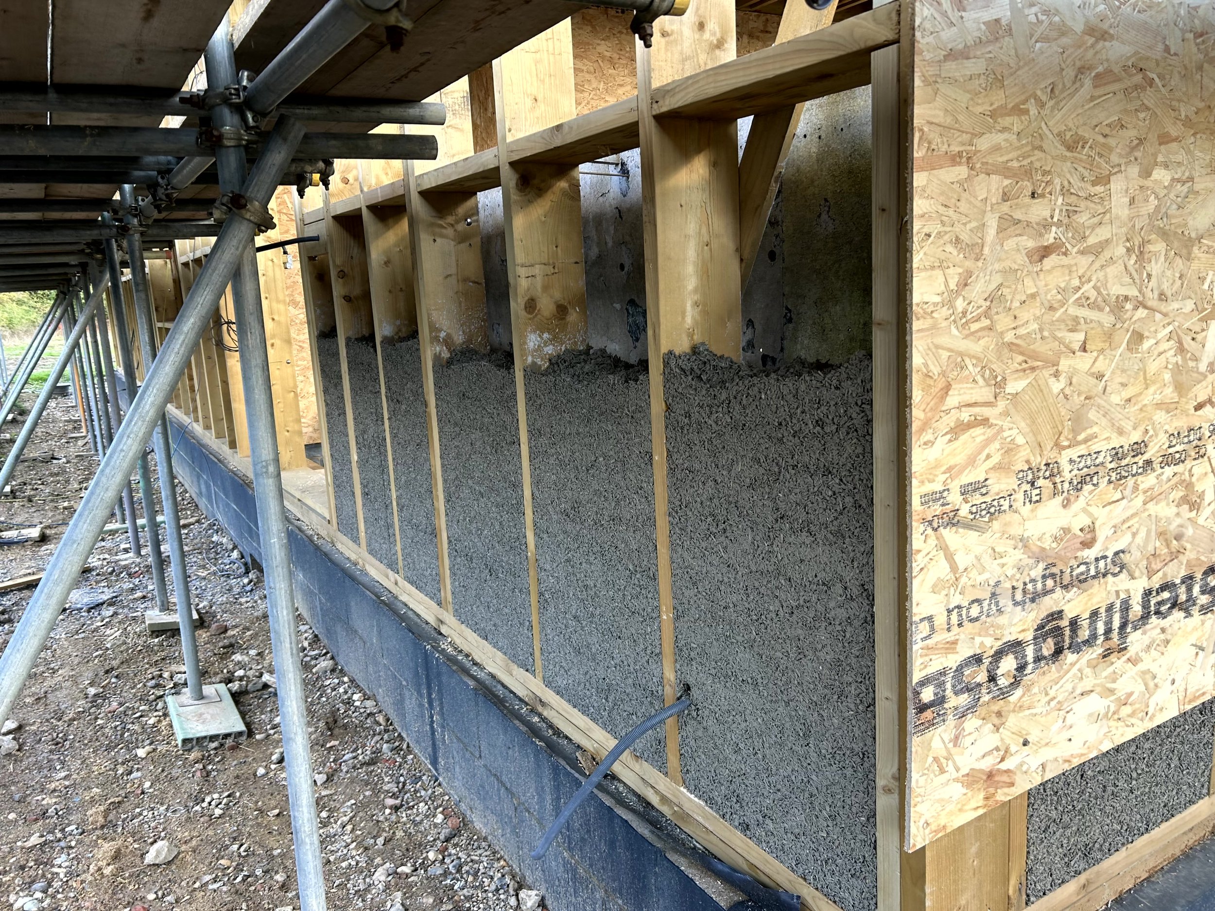 Access scaffold tower set up under the ridge of the roof space, with the stone gable wall and original oak roof timbers visible