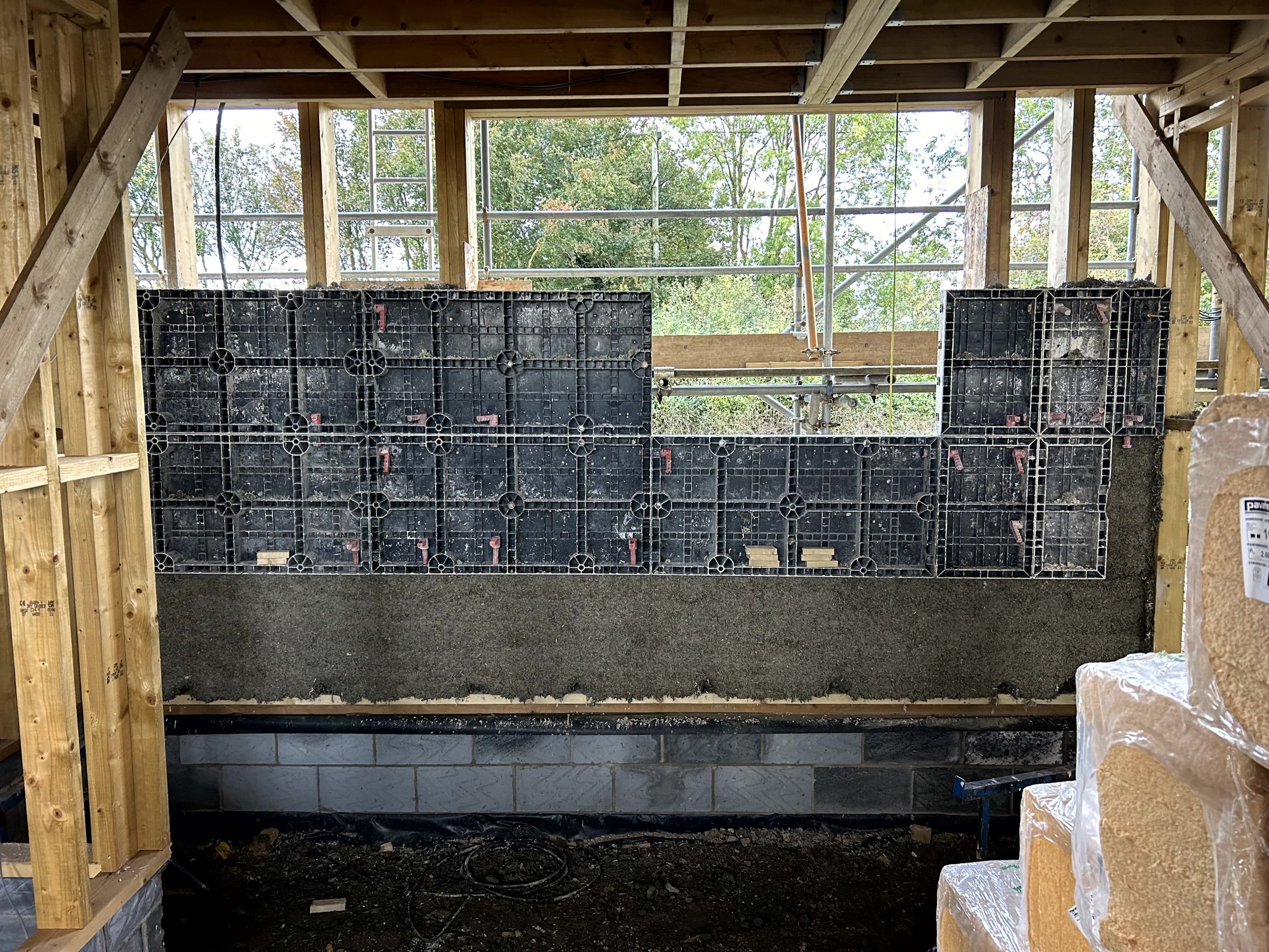 Sprayed hempcrete on a sloped wall in a low room under the eaves, with a window and insulation material on the floor