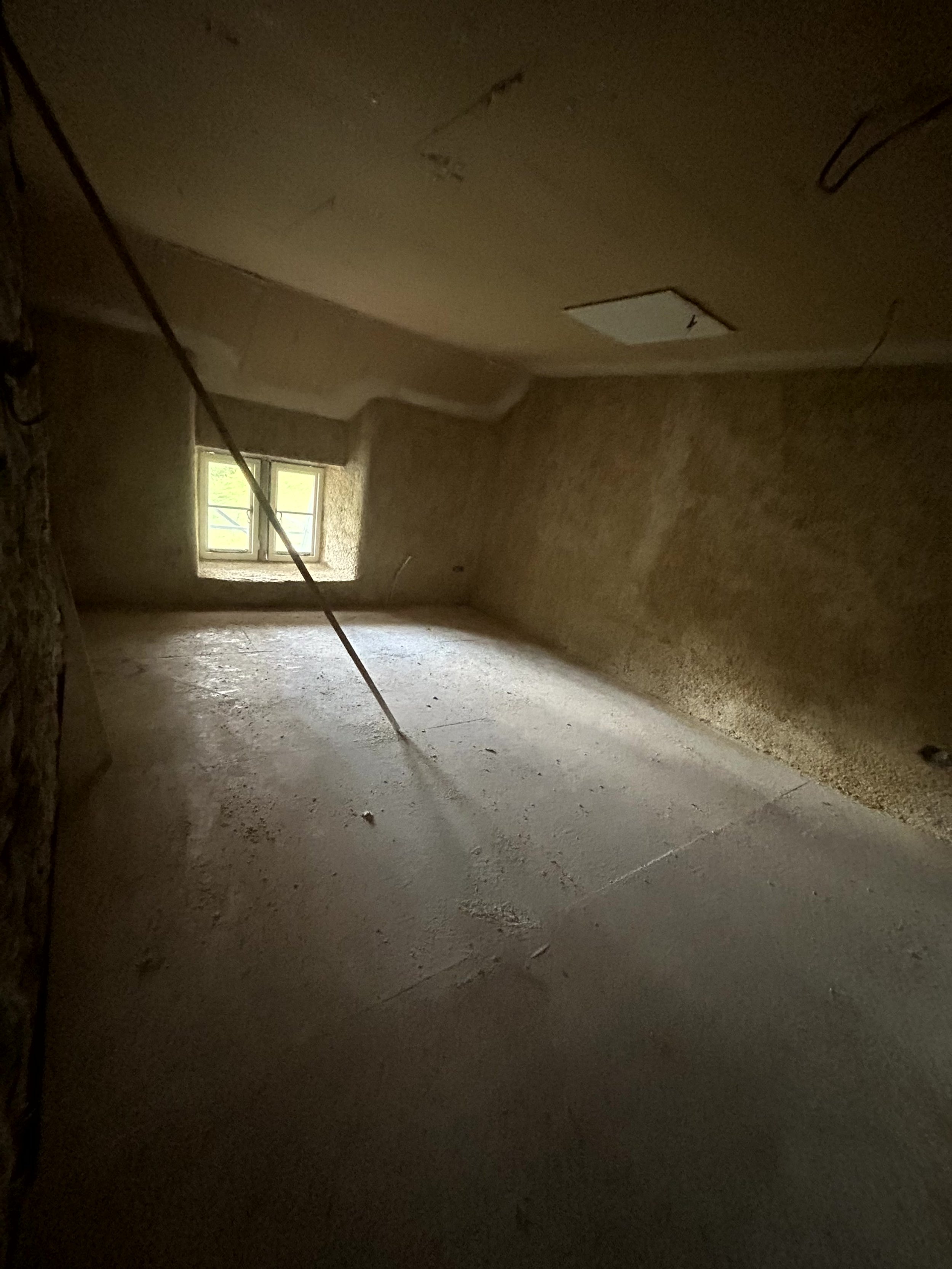 Finished, plastered room ready for decoration, lit by daylight from the window