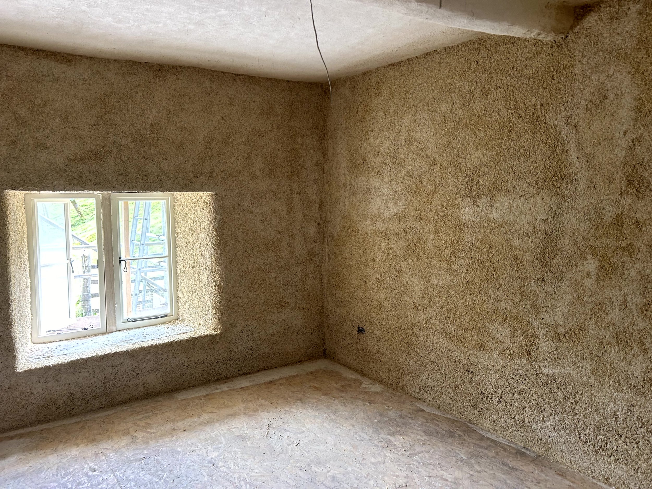 Close-up of hempcrete cast between timber studs on the building's exterior wall, with OSB sheathing fitted alongside