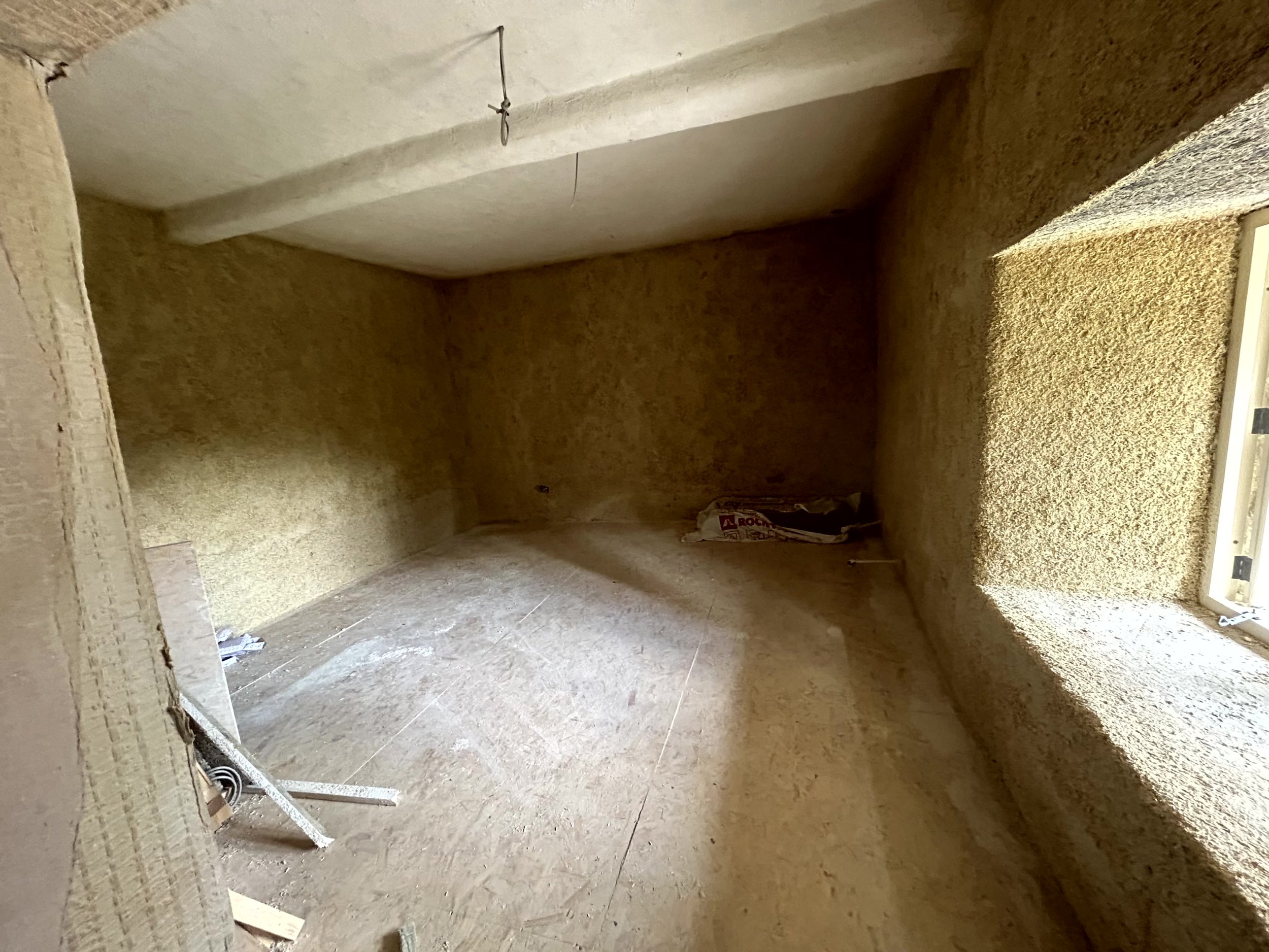 Formwork shuttering against the timber studs with hempcrete poured at the base, wood fibre boards stacked ready for external insulation